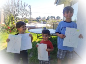kids show off their pictures of trees on a spring day 